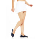 A white layered hip skirt with shorts is laid flat on a dark background, showing its elastic waistband.