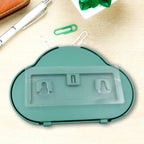 The back of a teal cloud-shaped phone holder with clear adhesive strips and hooks, on a desk.