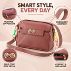 A mauve sling bag with a gold bow and colorful charms, highlighting multiple zip pockets and crossbody comfort.