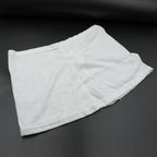 A white layered hip skirt with shorts lies folded on a dark gray surface.