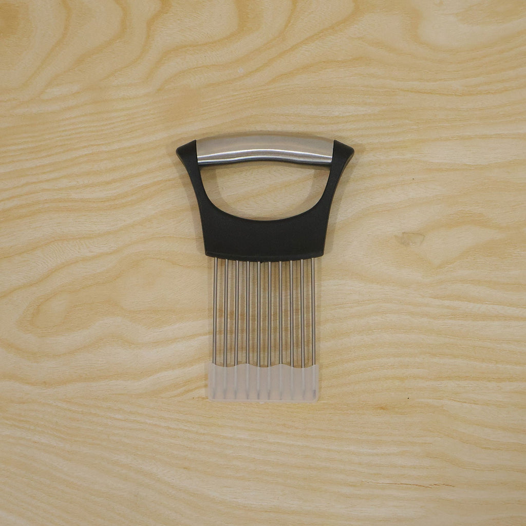 A black and silver onion holder with a white protective guard is centered on a light wooden background.