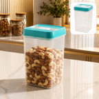 A clear plastic storage container with a teal lid, filled with cashews and almonds, on a kitchen counter.