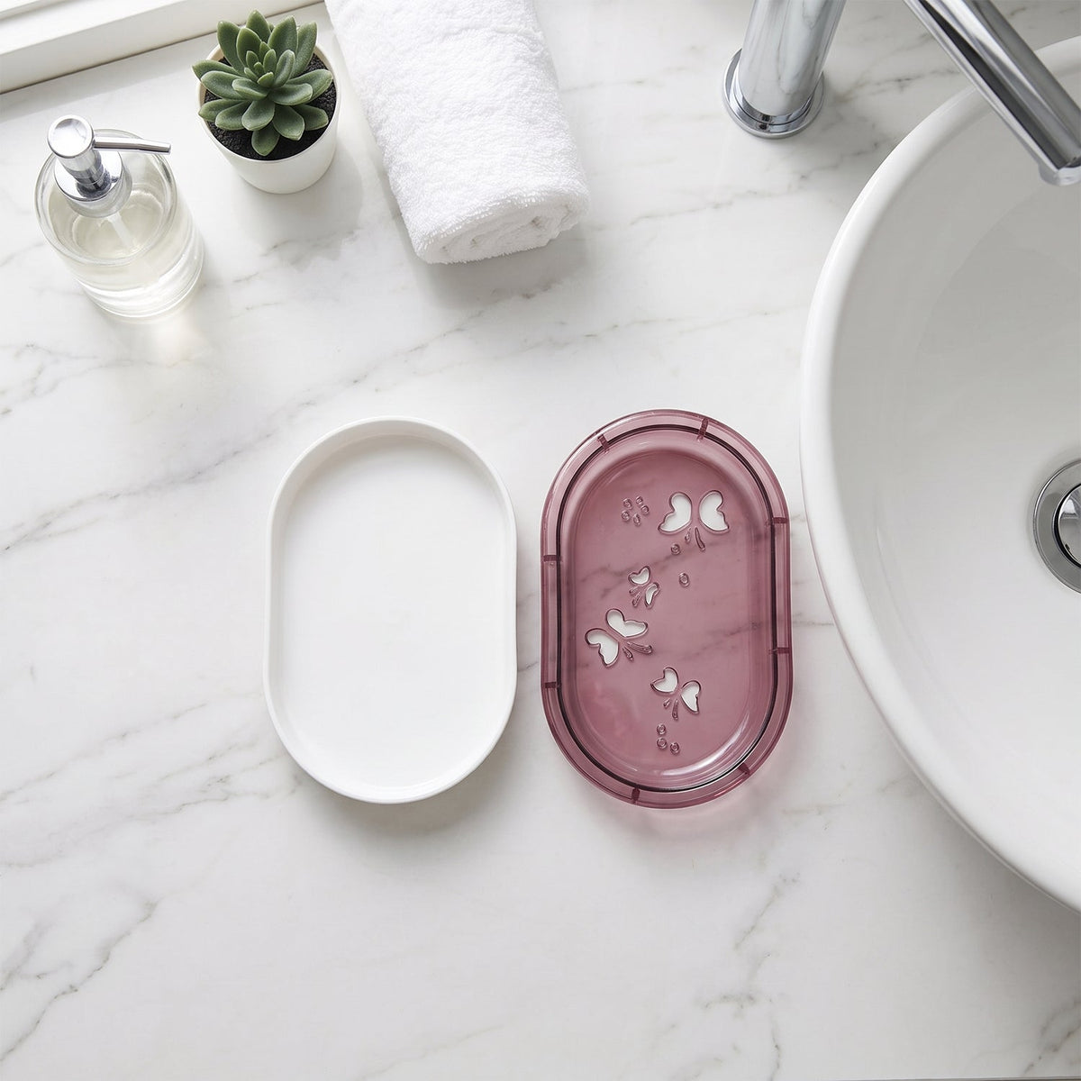 Top-down view of the white soap case base and the pink butterfly-patterned lid on a marble counter next to a sink.