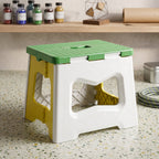 A green, white, and yellow plastic folding stool sits on a speckled counter with various craft supplies in the background.