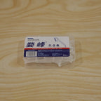 A clear plastic storage box filled with white dental floss picks sits on a light wooden surface.