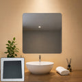 A square mirror with rounded corners hangs above a white sink in a modern bathroom setting