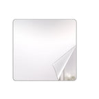 A square mirror with rounded corners has a corner of its protective film peeled back, revealing a reflection.