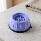 A single purple anti-vibration pad with a black base, resting on a speckled grey countertop next to a folded towel.