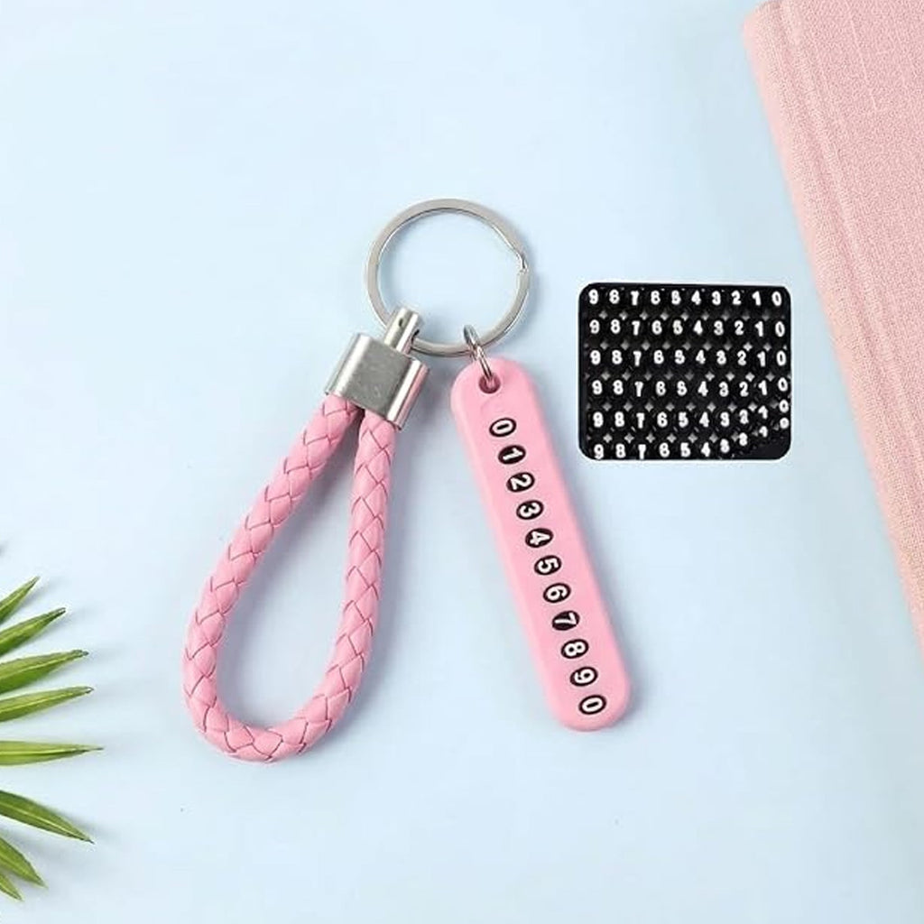 A pink braided wrist loop keychain with a pink number tag and a sheet of number stickers on a light blue surface.