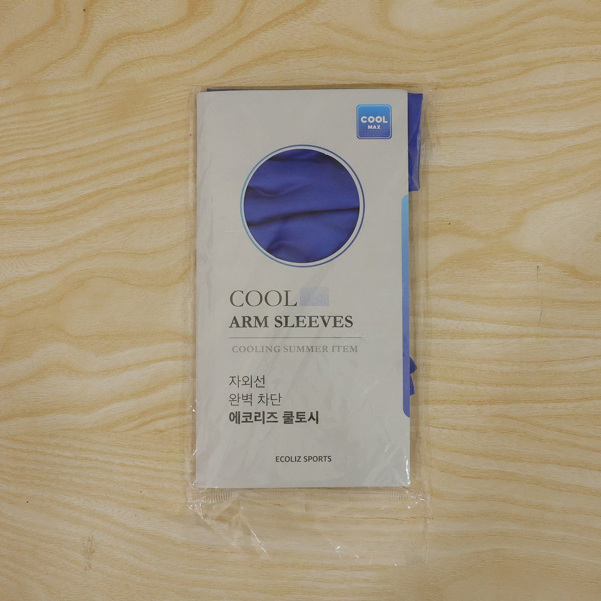 A packaged pair of "Cool Arm Sleeves" by Ecoliz Sports is displayed on a light wooden surface.