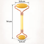 A yellow jade facial roller with rose gold frame is displayed with its dimensions of 14 cm length and roller widths of 5.8