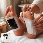 A person's feet with black and white foot pads applied, resting on a white towel in a bathroom setting