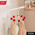 A cream multi-hook hanger with red ball tips, holding a light blue bag, a beige cap, and two scarves, hanging on a white
