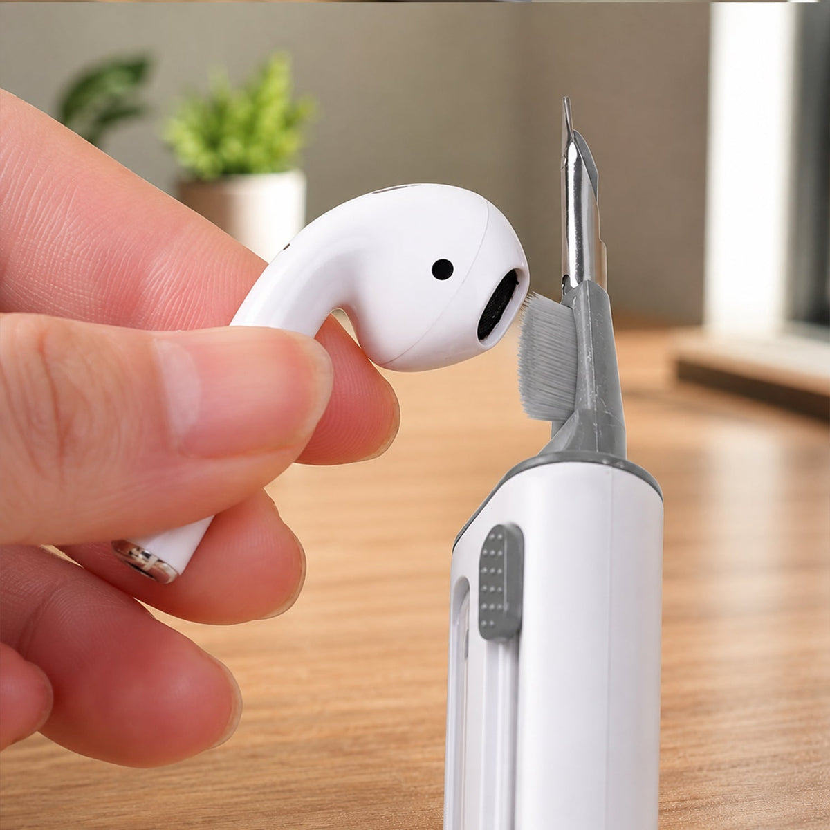 A hand holding a white earbud while the cleaning pen's small brush cleans the earbud speaker.