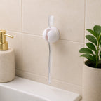 A white toothbrush holder clip on a tiled wall, holding a clear toothbrush above a sink, with a soap dispenser and – view 8