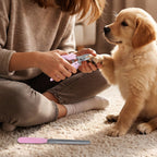 A person sitting on a rug, trimming a golden retriever's nails with the pink clipper, filer nearby.