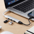 Silver 4-port USB hub connected to a laptop, with two USB drives plugged in