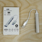 Silver 4-port USB hub next to its white packaging box on a light wooden surface.