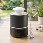 Black and white mosquito killer lamp with its USB cable on a wooden table with a folded cloth and plants.