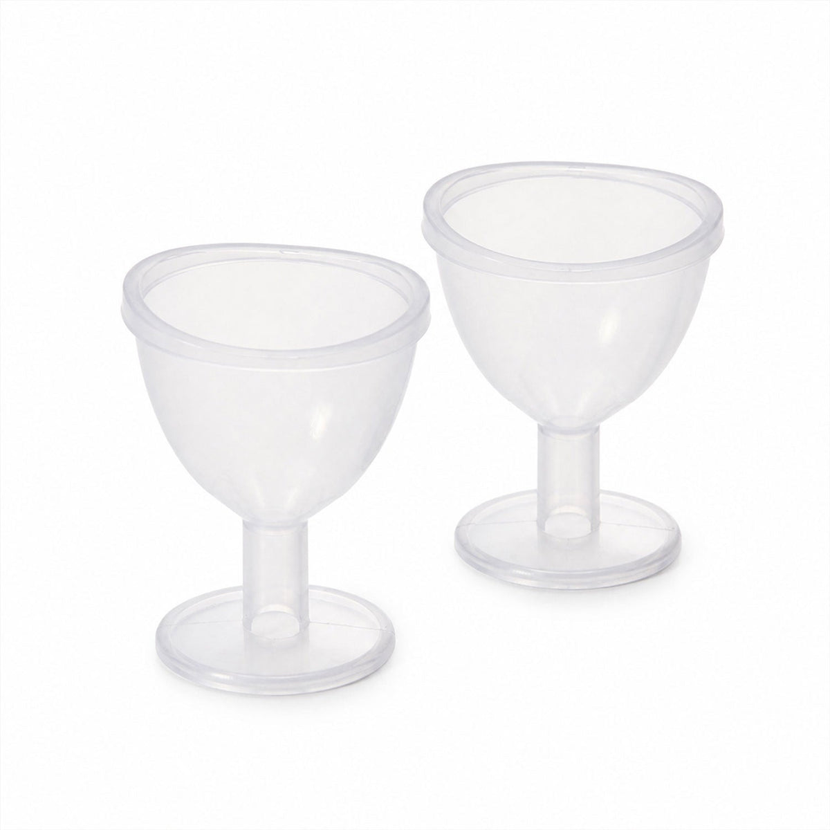Two identical clear plastic eye wash cups with short stems and wide bases are displayed side-by-side on a plain white