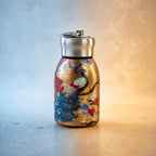 Golden stainless steel vacuum bottle with a peacock print, surrounded by water droplets and steam, indicating hot and cold