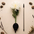 The disassembled white chrysanthemum solar light components laid out on a textured beige surface with decorative stones and