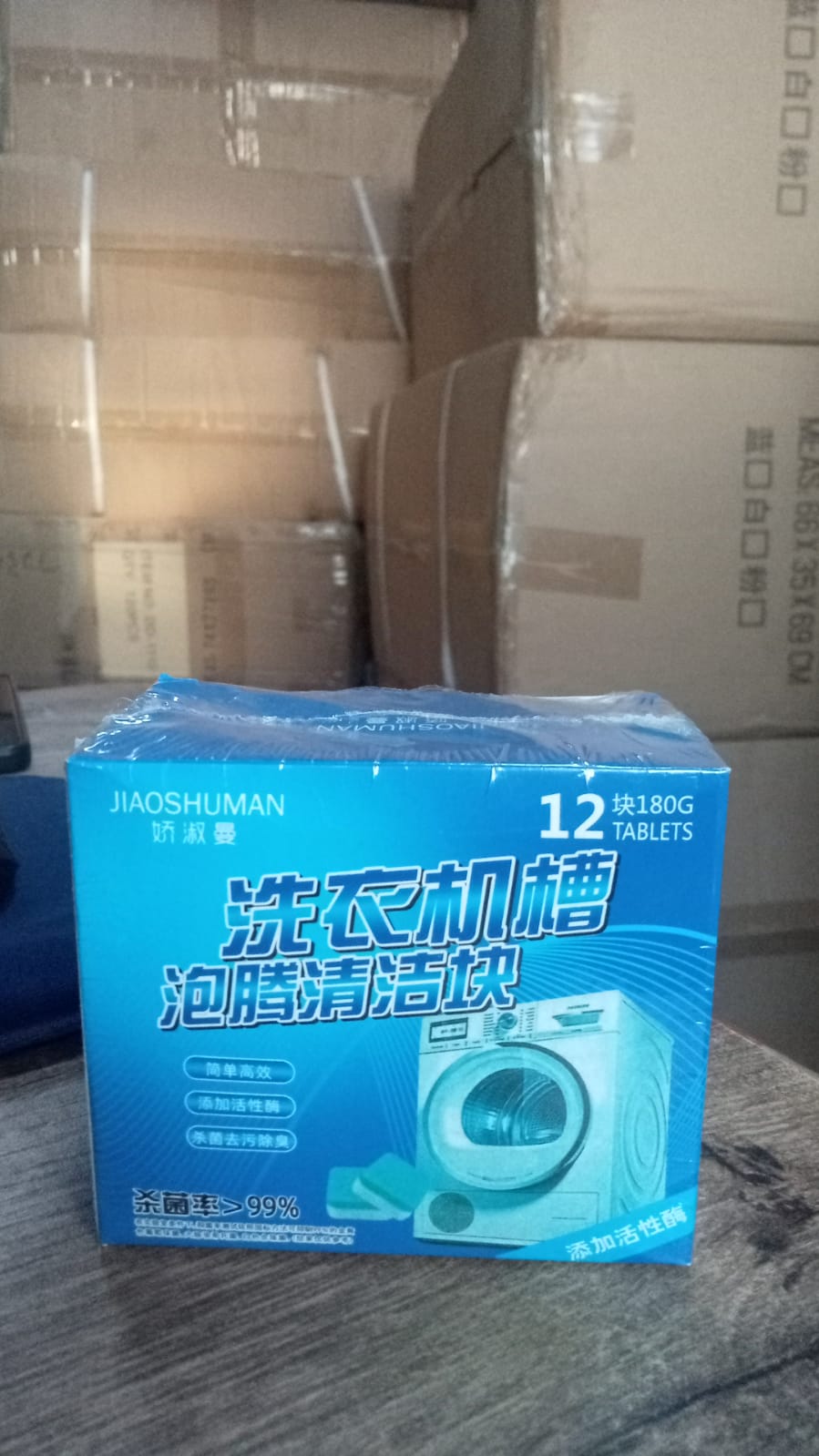 A blue box of JIAOSHUMAN washing machine cleaner tablets, with Chinese text, on a wooden surface.
