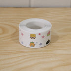 A single roll of white sealing tape with colorful cartoon characters on a light wooden surface.