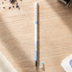 A white and blue pen refill with a small light blue cap on a wooden desk, surrounded by dried lavender.