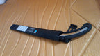 A black folding hand saw with a silver blade and its black cover are laid on a textured golden-brown surface.