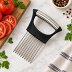 A black and silver onion holder with ten prongs sits on a white marble counter next to sliced red tomatoes.