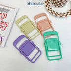 Four folded miniature chairs in purple, yellow, peach, and teal are arranged next to a patterned cup and book.