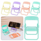 Four miniature foldable chairs in pastel yellow, purple, peach, and teal, with a phone resting on a purple stand. – view 9