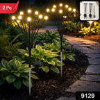 Two solar firefly garden lights with glowing bulbs stand in a garden, with a '2 Pc' label and '9129' code.