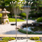 Two solar firefly lights with silver stems and white bulbs stand in a Japanese-style garden with raked gravel.