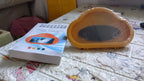 A yellow cloud-shaped phone holder and its white instruction manual on a textured surface.