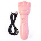 A pink bear paw shaped massager with a power button and its coiled black USB charging cable are on a white background.