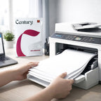 Hands load paper into a white printer next to a Century Splendour paper ream and a laptop.