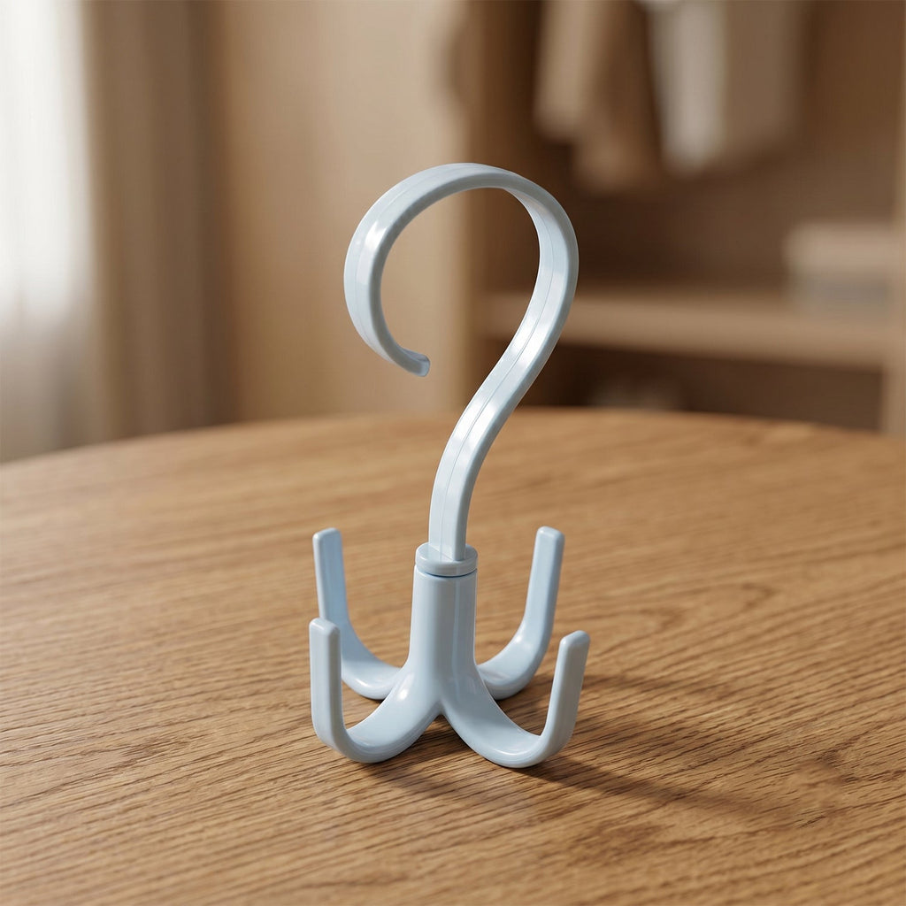 A light blue plastic rotating multi-hook hanger sits on a wooden table, with a blurred background of a room.