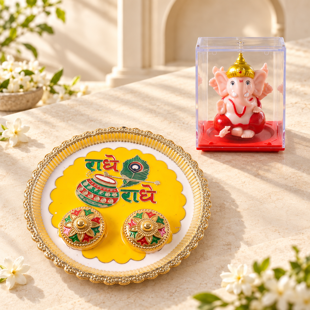 A gold-rimmed white and yellow pooja thali with Radhe Radhe text and two small containers sits beside a Ganesha idol in a