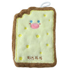 A cartoon cheese toast-shaped microfiber towel with a pink nose and blue eyes, and yellow dots, is displayed on a white