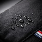 Close-up of water droplets beading on the waterproof black fabric of the sling bag.