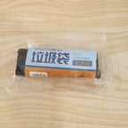 A clear plastic-wrapped roll of black garbage bags with a blue and brown label on a wooden surface.