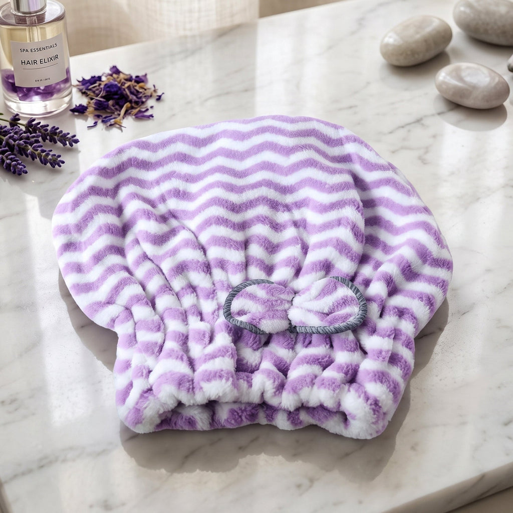 A purple and white chevron microfiber hair towel with a grey bow, on a marble surface with lavender and stones.