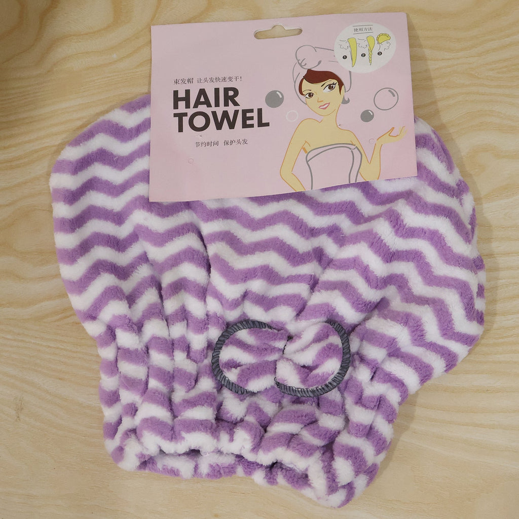 A purple and white chevron microfiber hair towel with a grey bow, displayed with its pink packaging on wood.