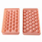 Two pink plastic ice ball trays, one with open spherical molds and the other with covered molds.