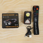 The headlamp, its strap, charging cable, and product box laid out on a light wooden surface.