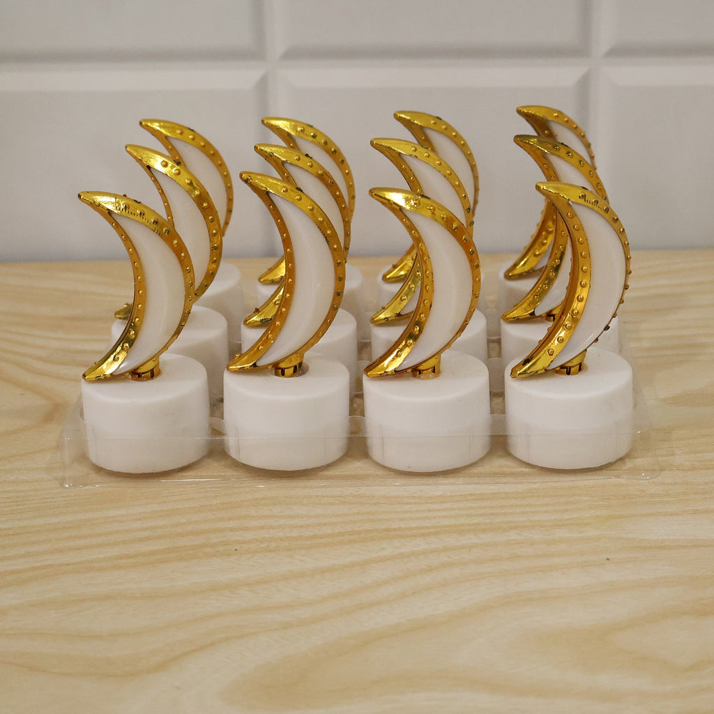 Eight golden crescent moon LED tealights in clear plastic packaging on a light wooden surface.
