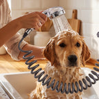 A golden retriever dog being bathed in a kitchen sink with the handheld shower spray, covered in white soap suds.