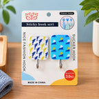 Two patterned adhesive hooks, one with blue dolphins and one with blue sailboats, displayed in packaging on a wooden surface.